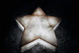 Close-up of a glowing golden star symbol etched on a dark blue textured background.