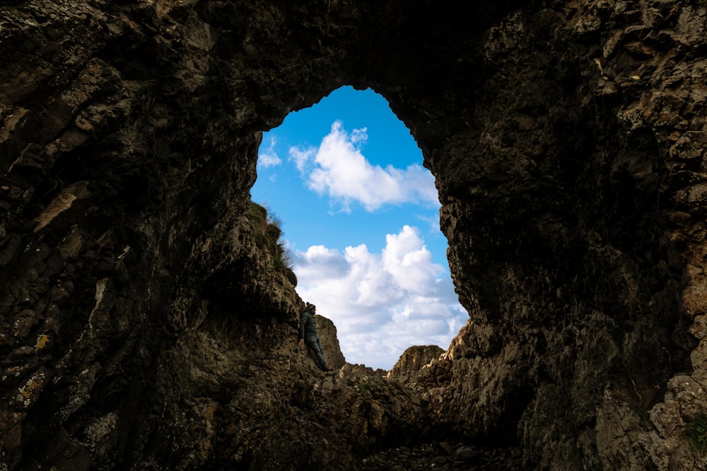 a hole in the rock with a sky background