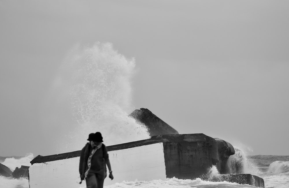 a person walking on a beach next to a large wave