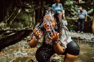 A smiling person gently cleansing their face with water splashing softly.
