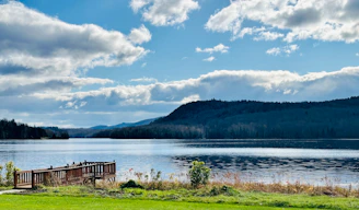 A serene lakeside view with a small dock and a medical professional enjoying the peaceful surroundings.