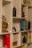 A neatly arranged bookshelf featuring a variety of books, some of which are titled 'Good to Great' and 'The 7 Habits of Highly Effective People'. A decorative metal sculpture resembling a tree with round, golden leaves sits prominently on the shelf, along with marble-patterned vases. Small potted plants add a touch of greenery, while a bicycle-themed book provides a whimsical touch.