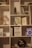 A bookshelf filled with various items, including books, decorative objects, and small plants. Books such as 'Delivering Happiness', 'Platform Revolution', and 'The Lean Startup' are visible. A small potted plant and a decorative tree with red leaves are also present. A dark-colored vase and a vintage-looking object resembling a gong are among the decorative items.