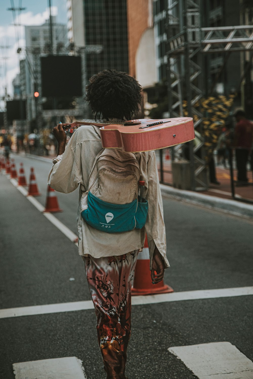 a woman walking down a street carrying a skateboard