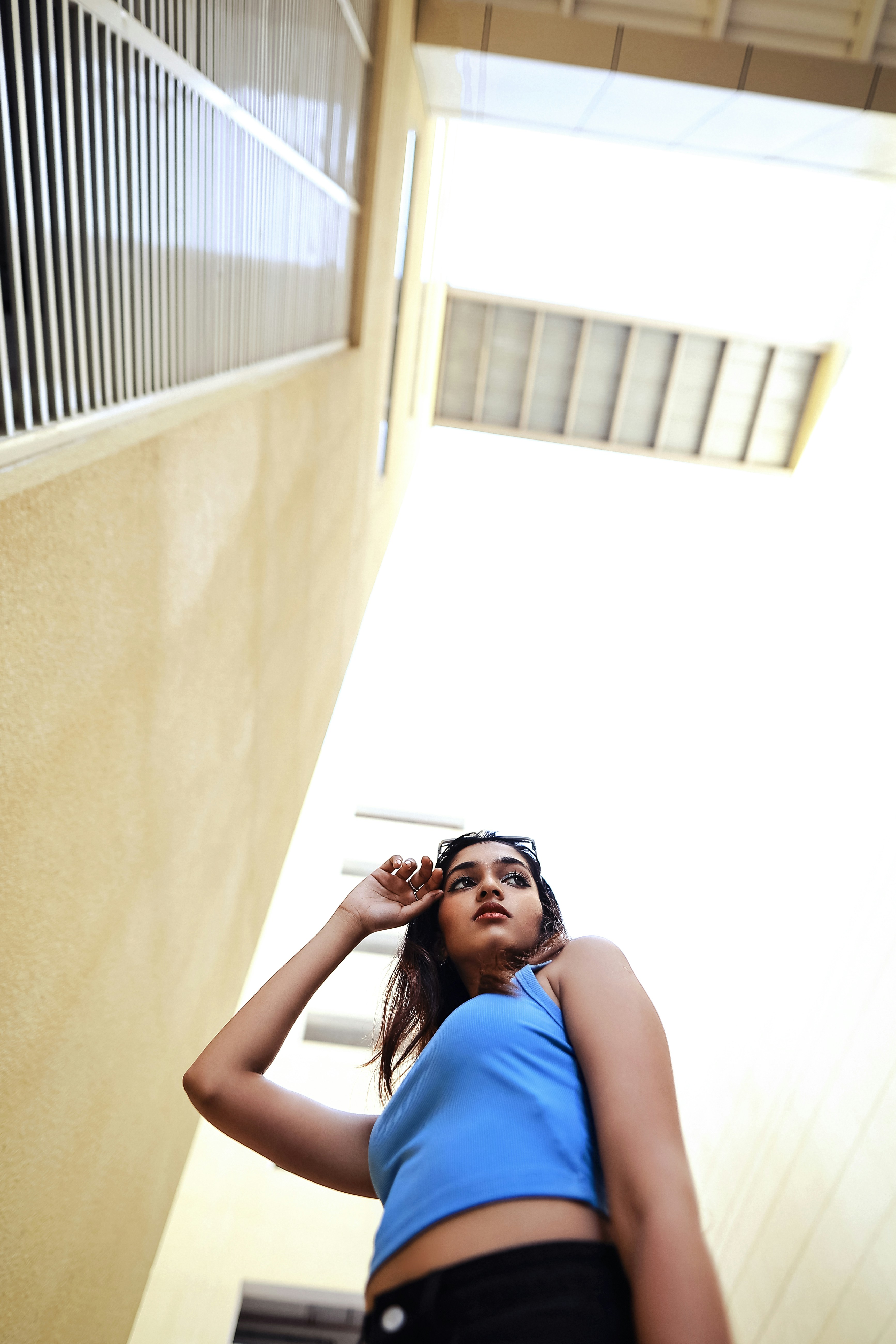 a woman in a blue top leaning against a wall