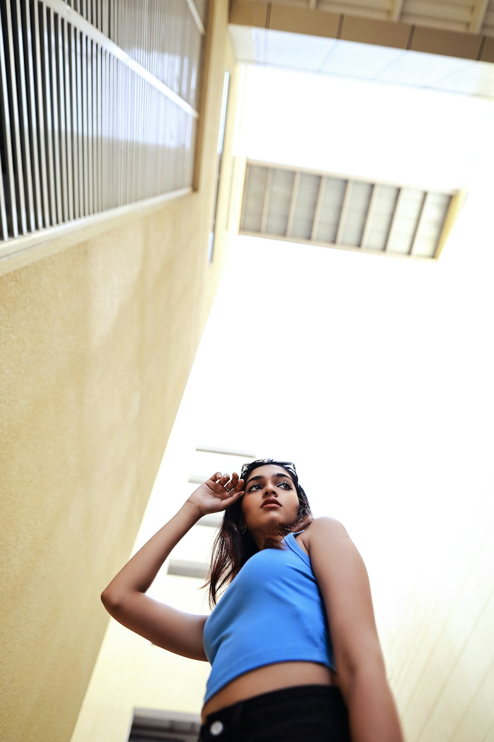 a woman in a blue top leaning against a wall