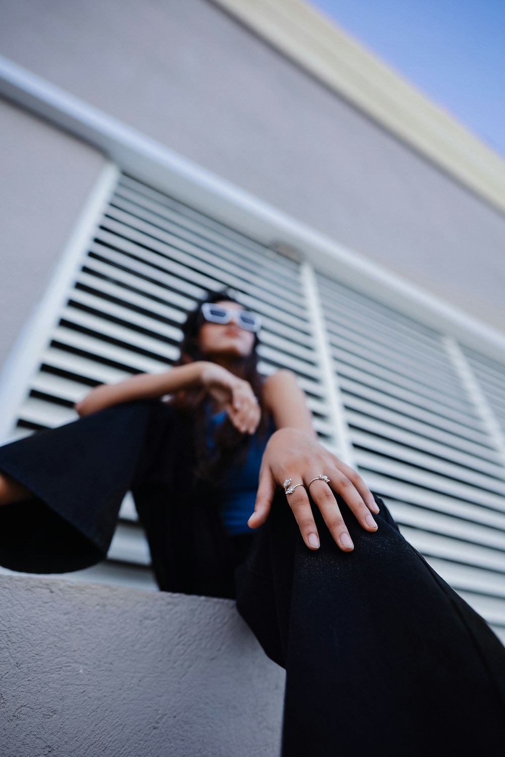 a woman wearing sunglasses sitting on a ledge