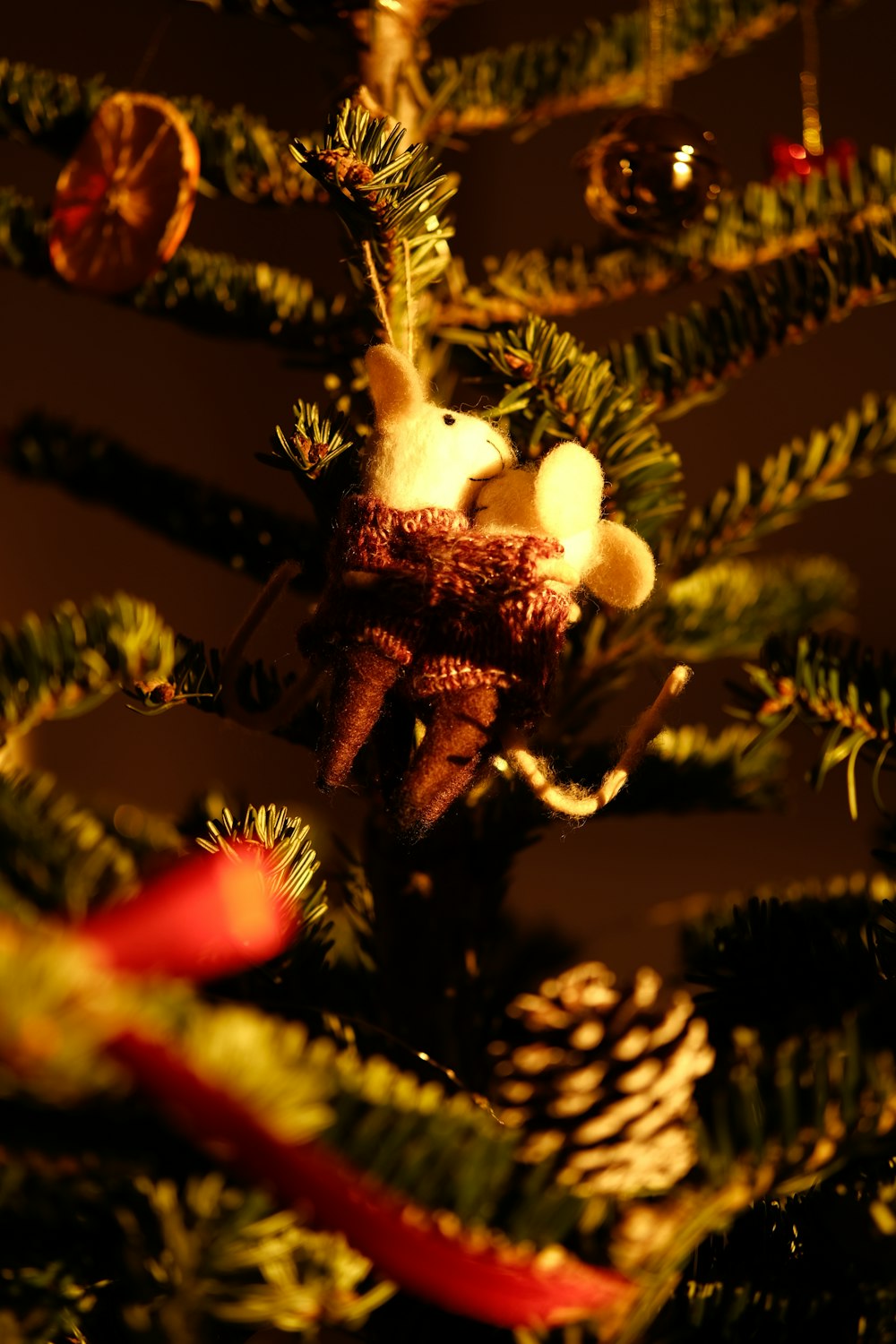 a teddy bear is sitting in a christmas tree