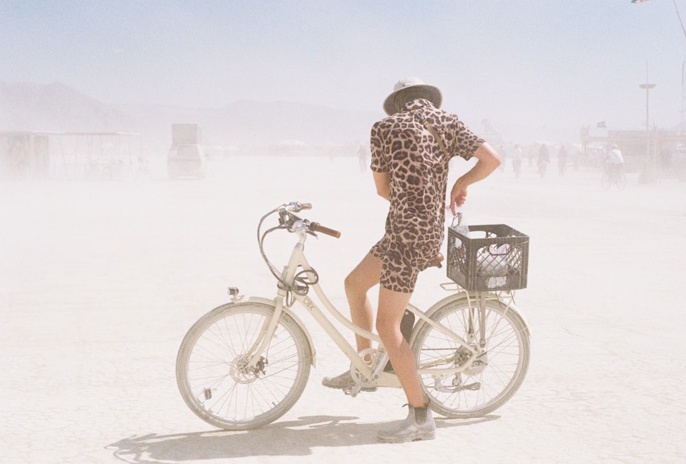 a man standing next to a bike in the desert