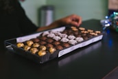 Smiling person holding a tray of freshly made chocolates ready to share.