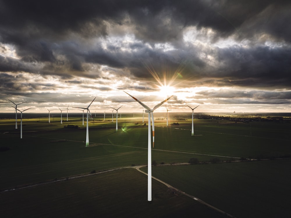 a group of windmills in a field under a cloudy sky