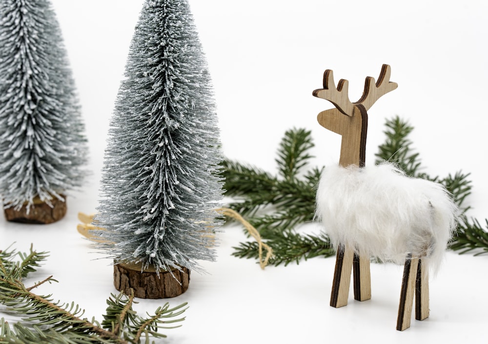 a small wooden reindeer standing next to a christmas tree