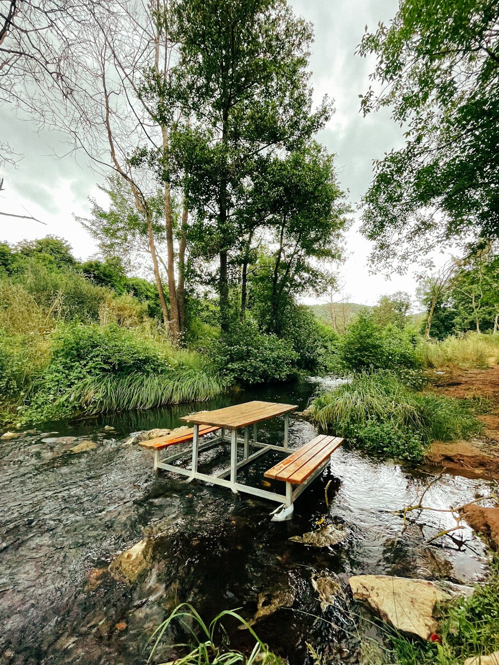 a wooden picnic table sitting on top of a river