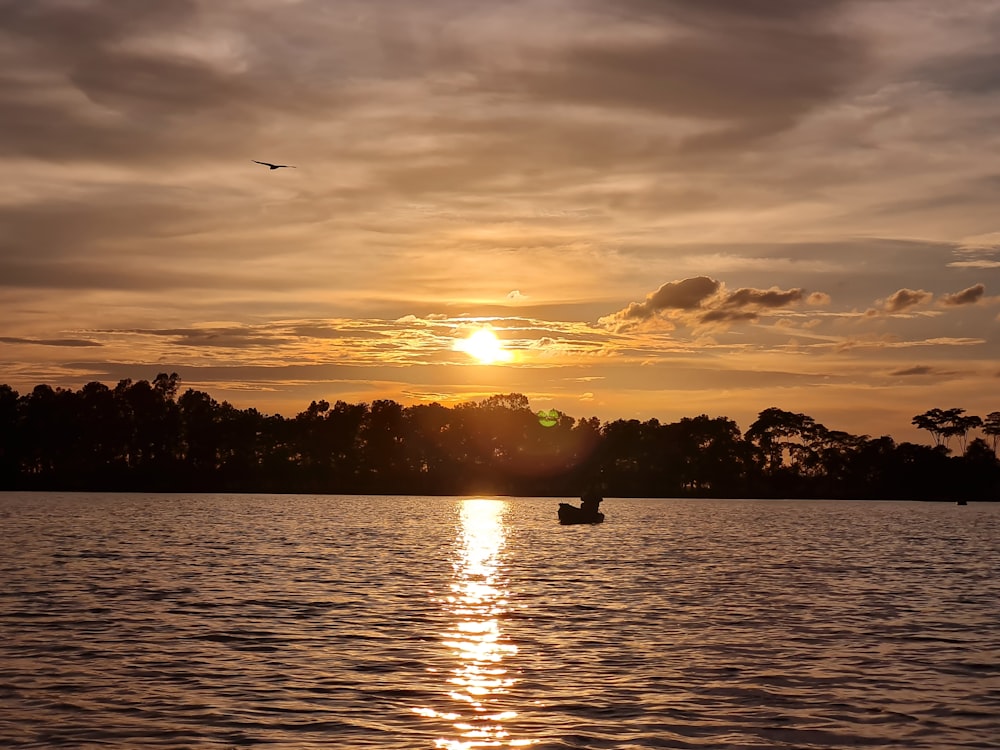 a boat floating on top of a lake under a cloudy sky