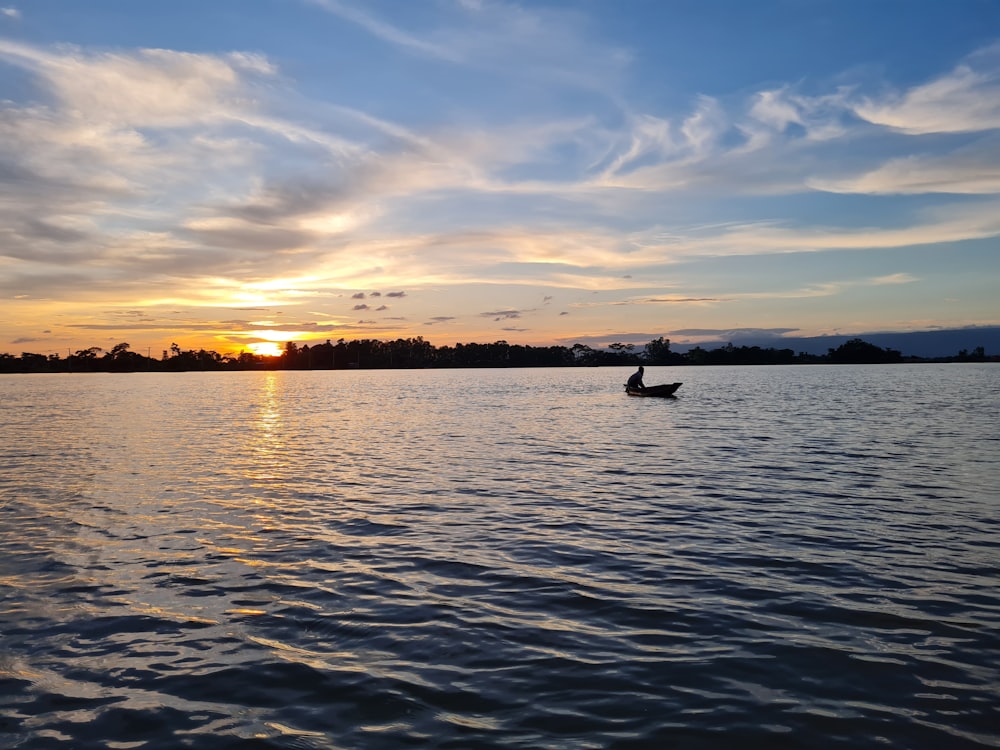 a person rowing a boat on a lake at sunset