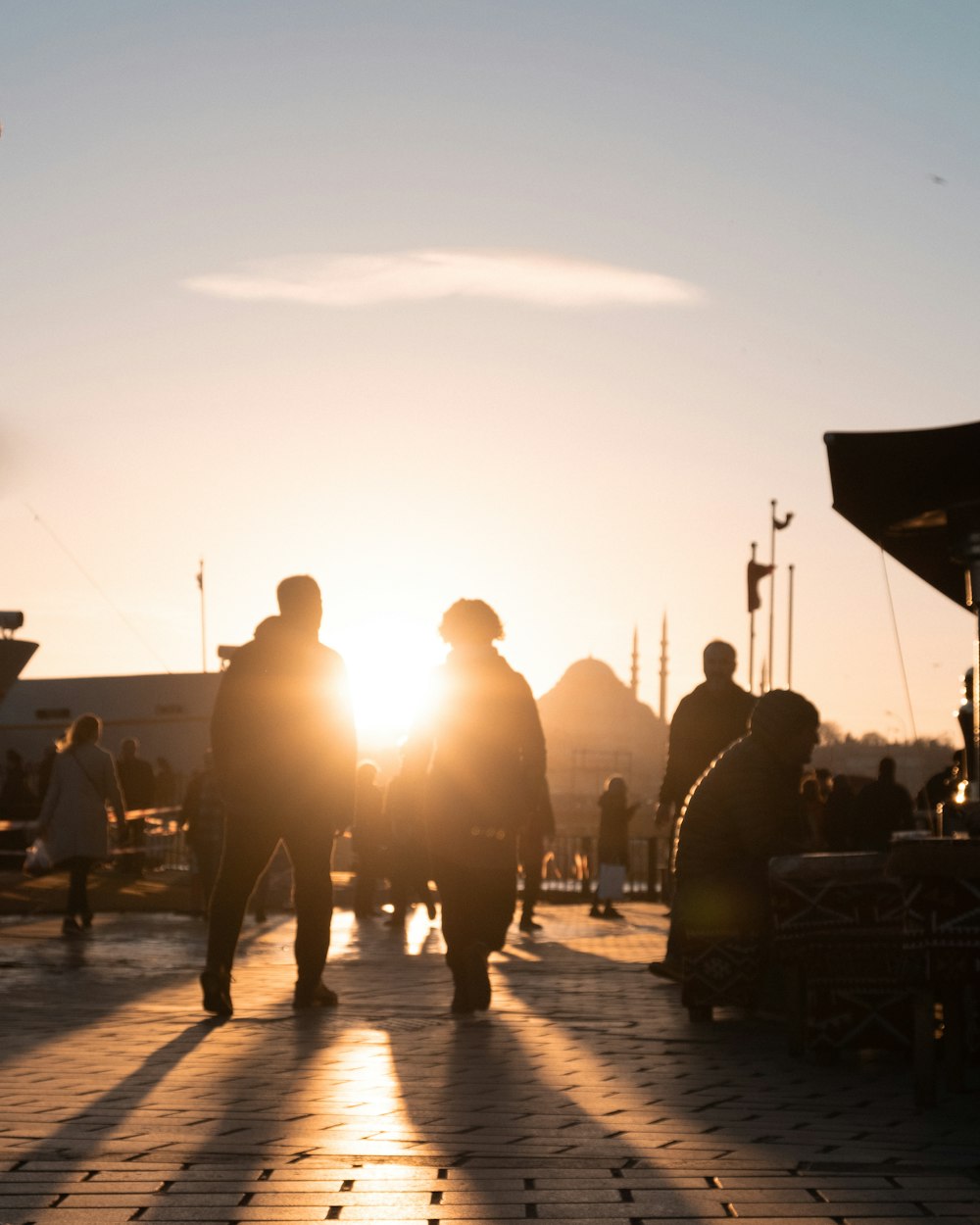 a group of people walking down a sidewalk at sunset