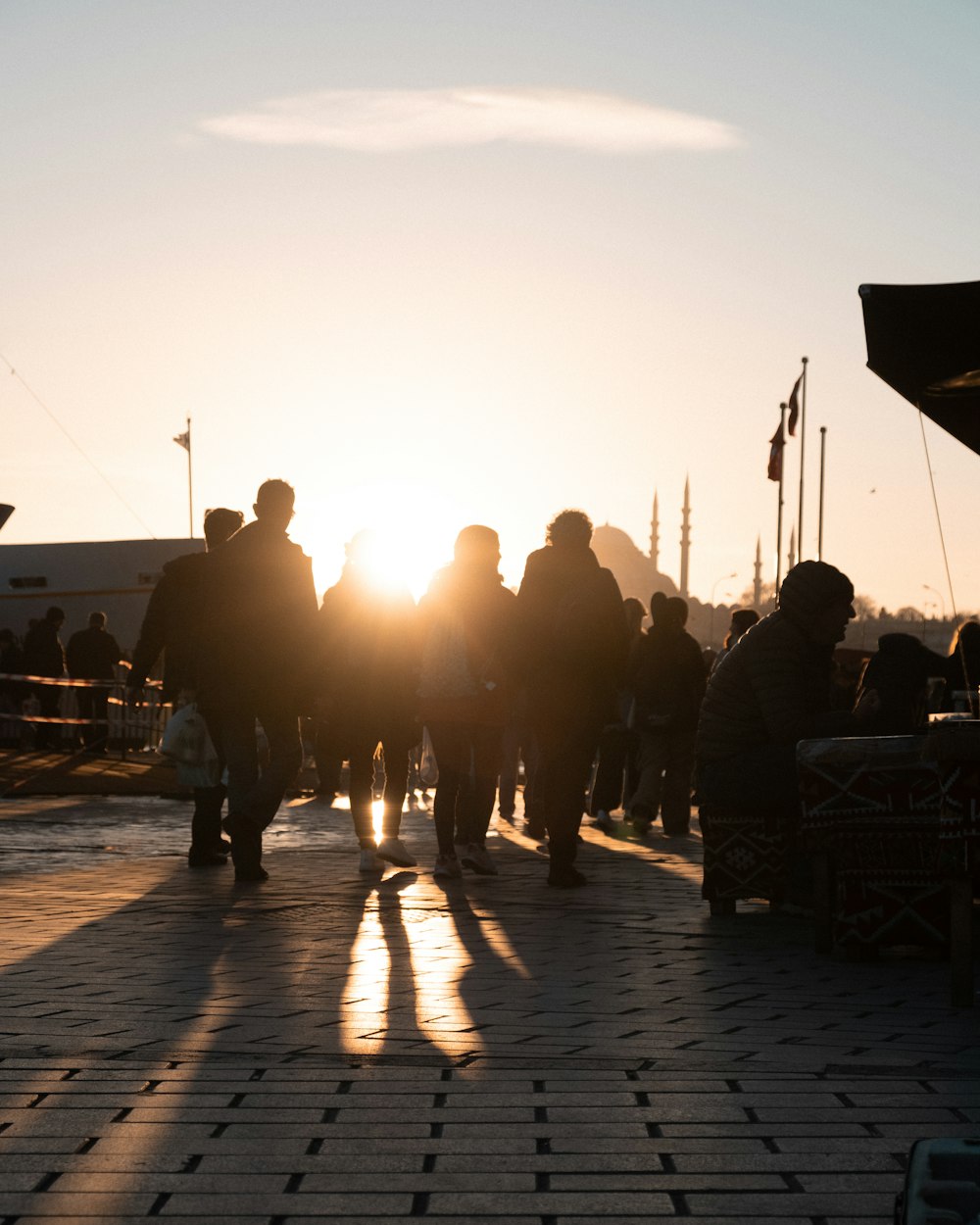 a group of people walking down a sidewalk at sunset