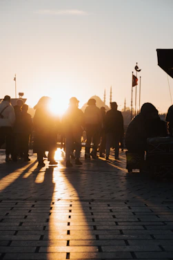 A warm group of pilgrims walking together near a historic mosque at sunset.