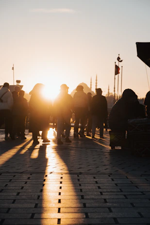 A serene scene of a group of pilgrims walking together near a mosque during sunset.