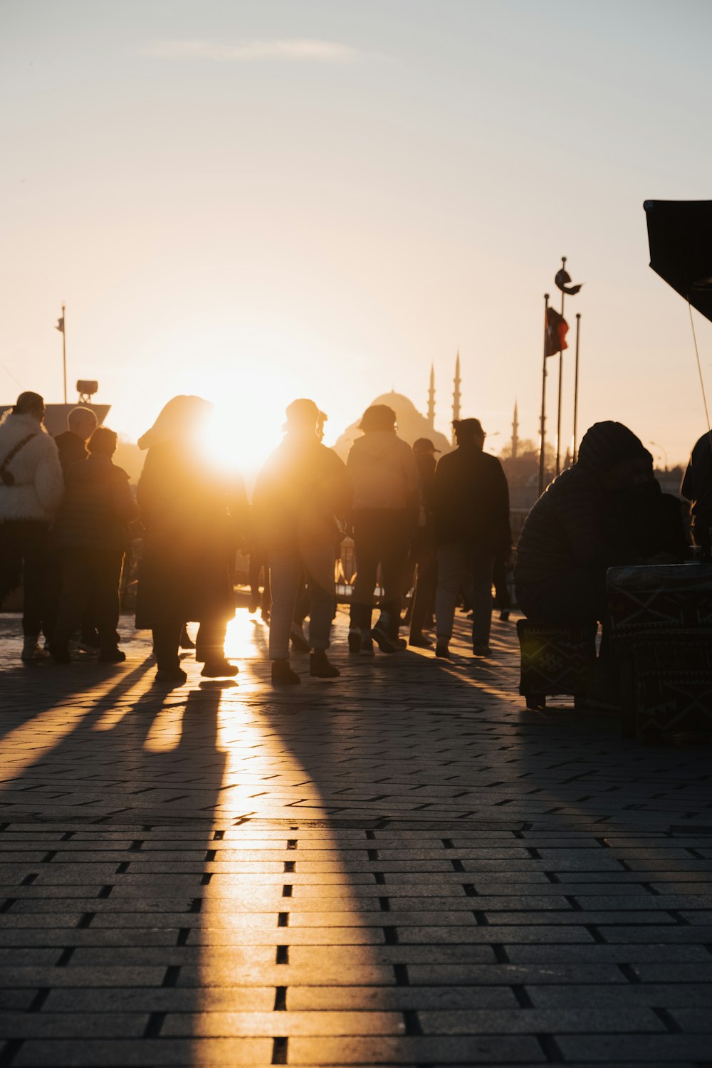 a group of people walking down a sidewalk at sunset