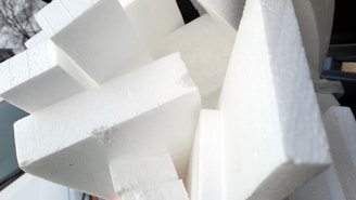 Close-up photo of EPS foam window mounting profiles neatly stacked in a workshop.