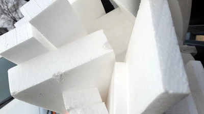 Close-up photo of expandable polystyrene sheets stacked neatly in a modern factory setting.