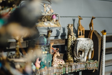 A collection of small ceramic animal figurines arranged on a wooden shelf.