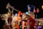 A decorative scene with large toy soldier figures dressed in traditional, colorful uniforms. The main figure is holding a trumpet, set against a vibrant background of lights and festive decorations.