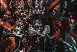 A vivid display of ornate carnival masks adorned with intricate designs, feathers, and embellishments. The masks appear to be part of a collection, demonstrating a variety of artistic styles and colors. Dazzling headpieces with gold, red, and blue tones catch the eye, while some masks feature delicate filigree and painted details.