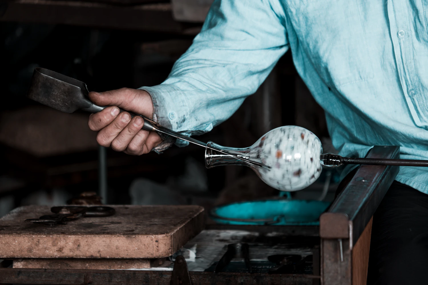 A glassblower at the Lauscha workshop turning a molten glass sphere on the pipe