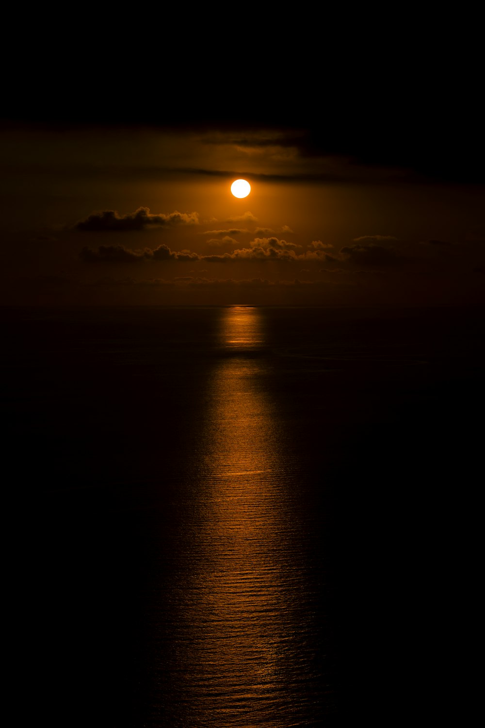 a full moon is seen over the ocean