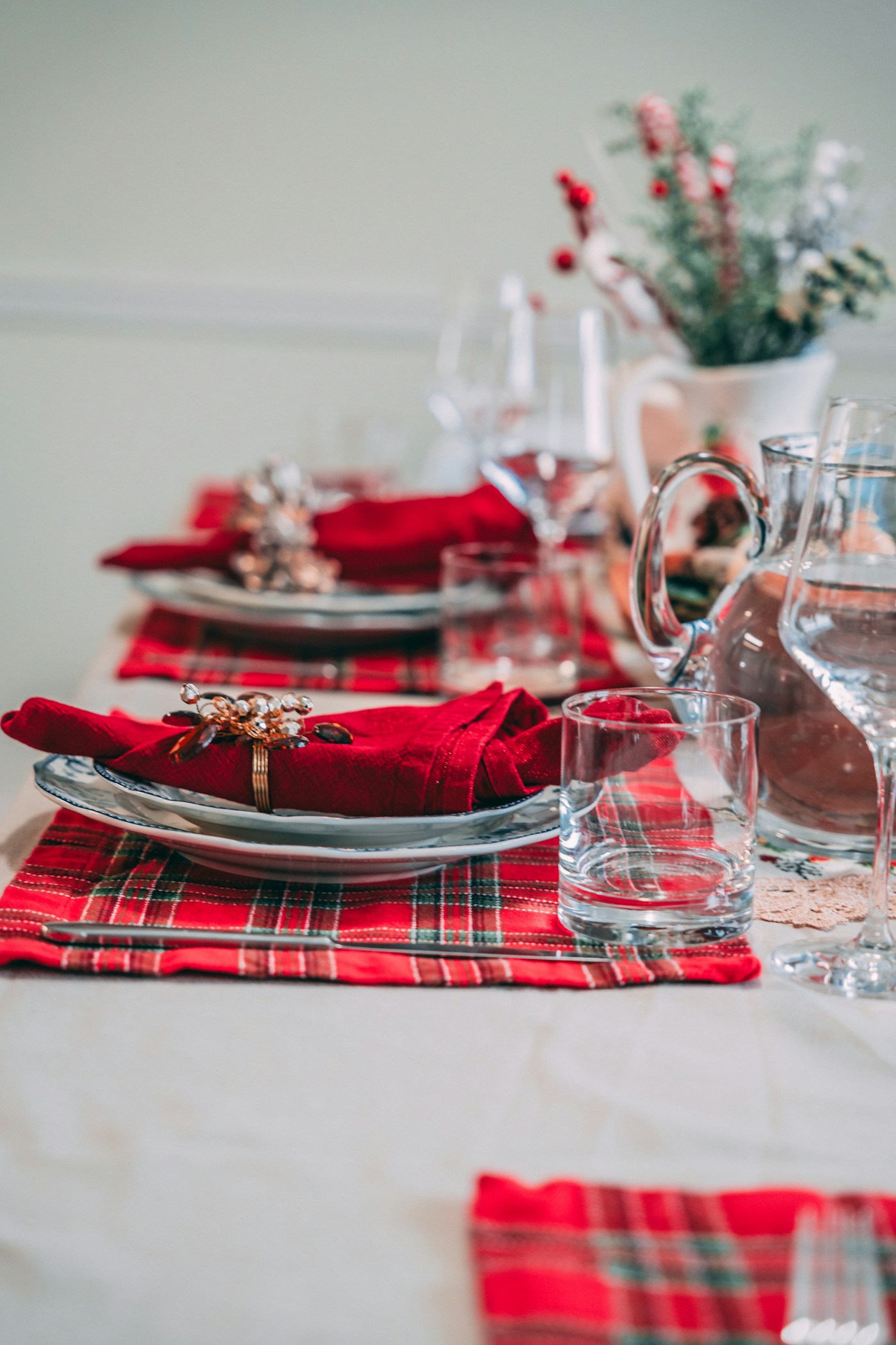 A holiday table set with repeated red napkins, clear glassware and simple plates.