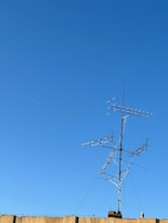 Modern wireless internet antenna against a clear blue sky.