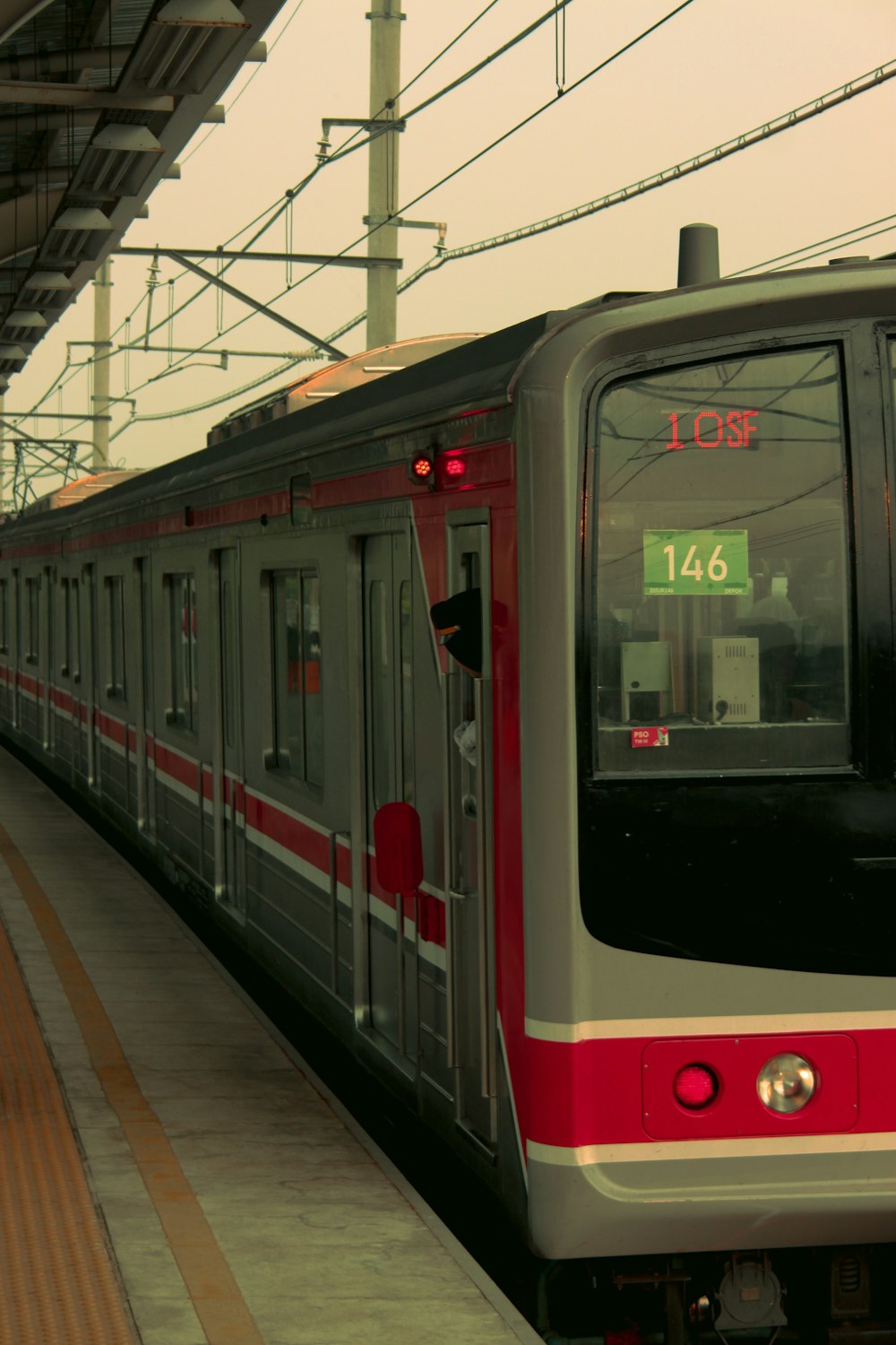 a red and silver train pulling into a train station