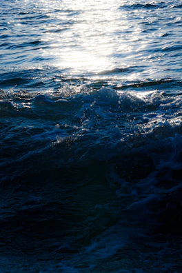 Sunlight sparkling over crystal-clear waves crashing gently on the shore nearby.