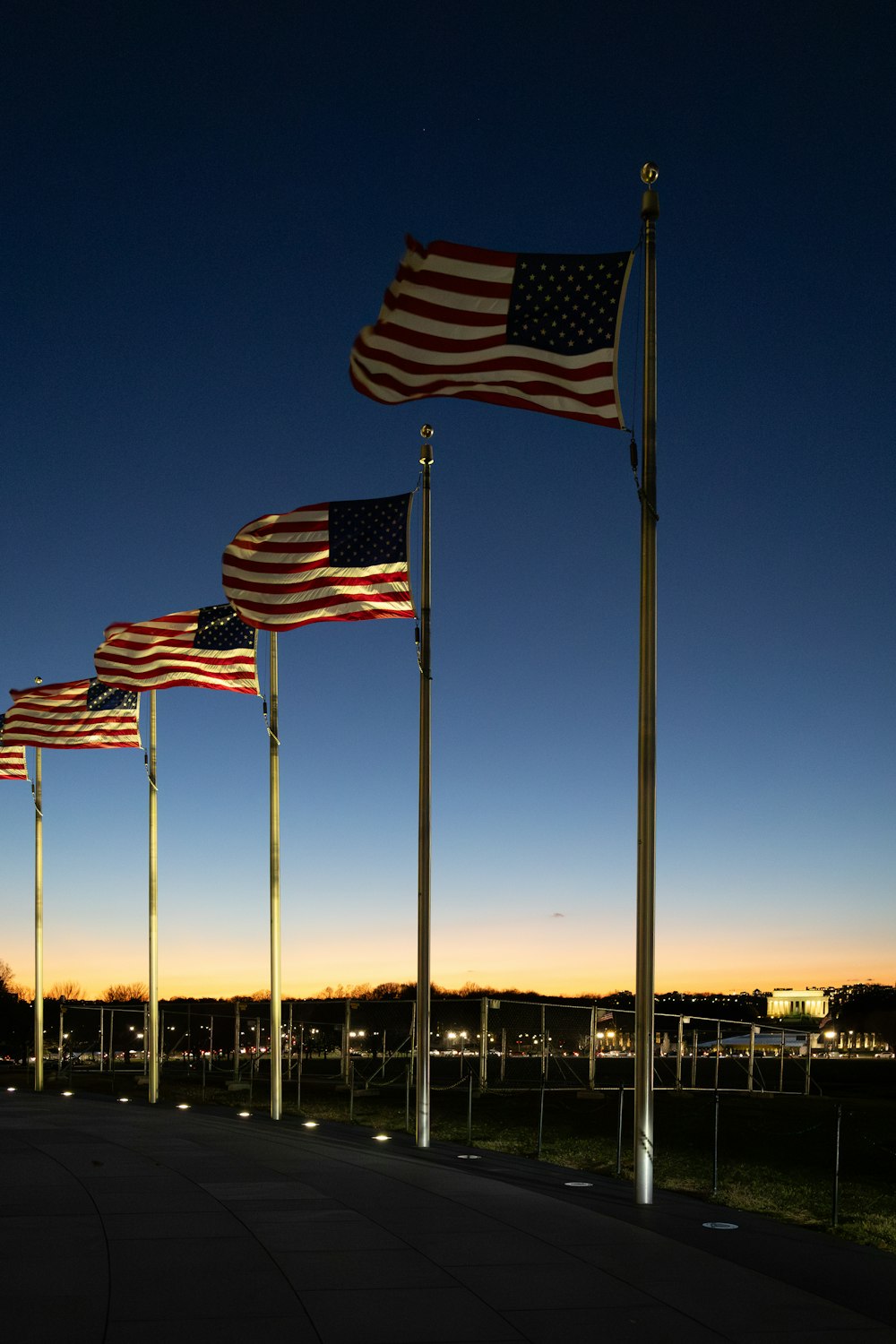 Uma fileira de bandeiras americanas em postes em um parque