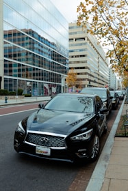 Fleet of premium executive cars lined up on a city street during daytime.