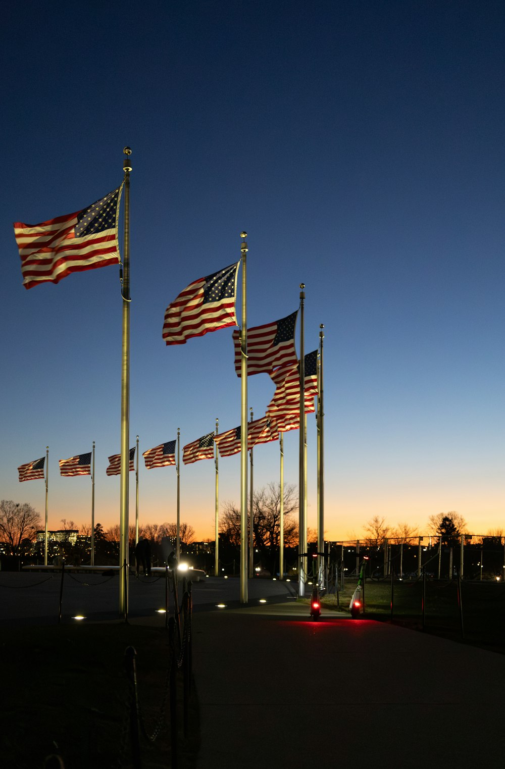 a row of american flags blowing in the wind