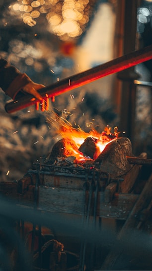 Close-up of skilled hands shaping a glowing piece of metal in a traditional workshop.