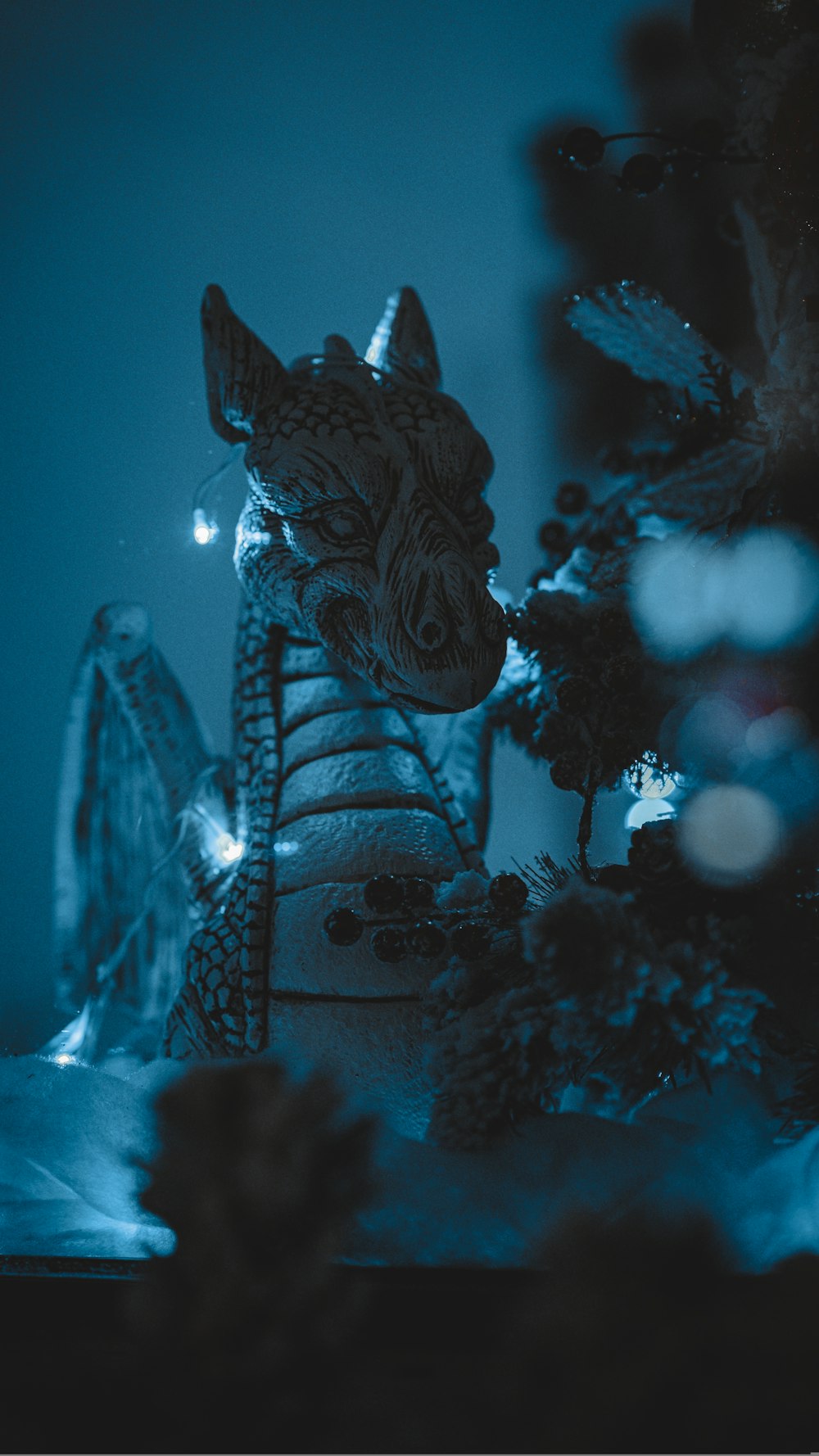 a statue of a dragon sitting next to a christmas tree