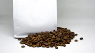 A premium coffee bag sealed and standing tall on a soft beige backdrop with rich coffee brown shadows.