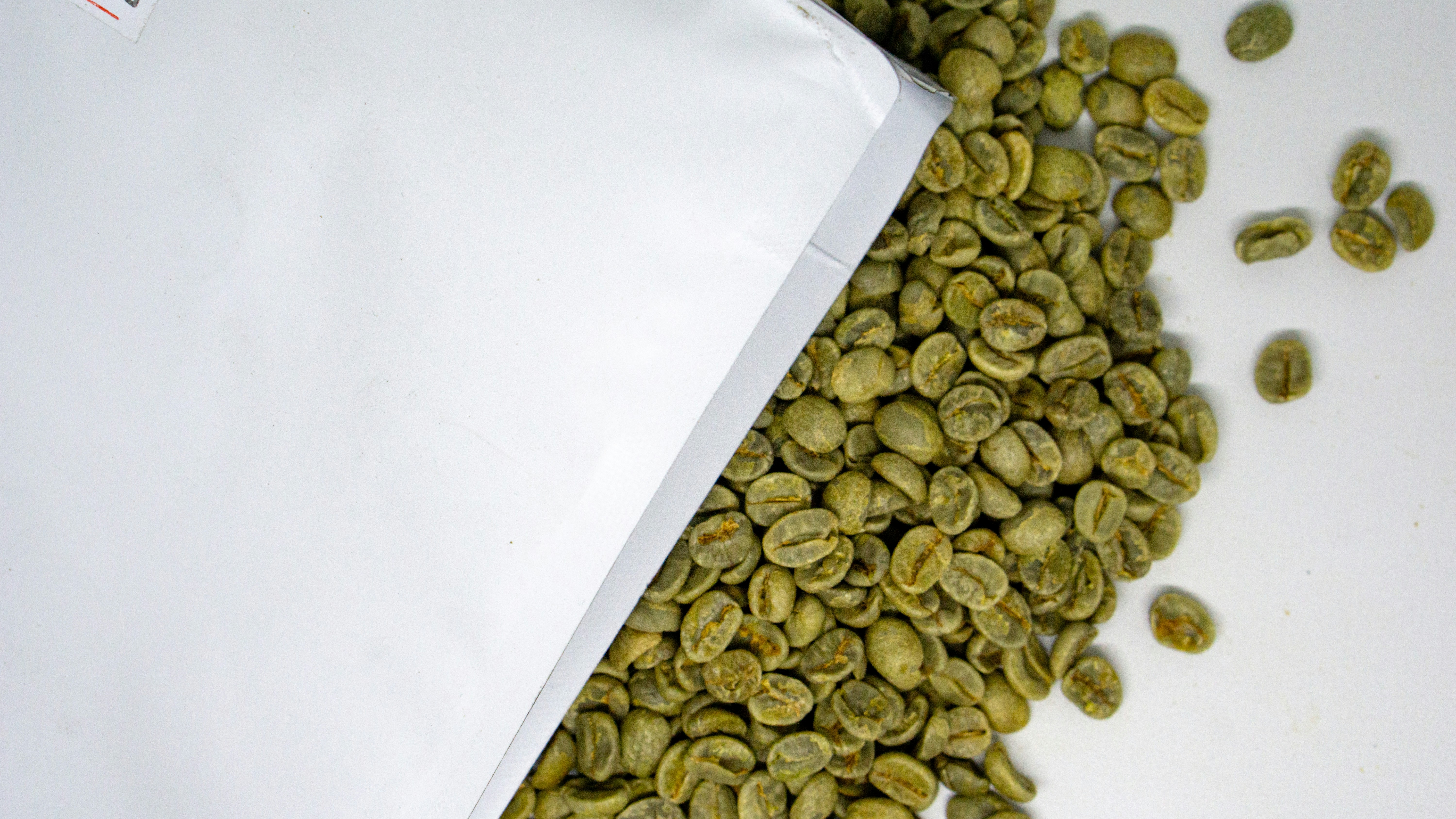 a white bag filled with green coffee beans