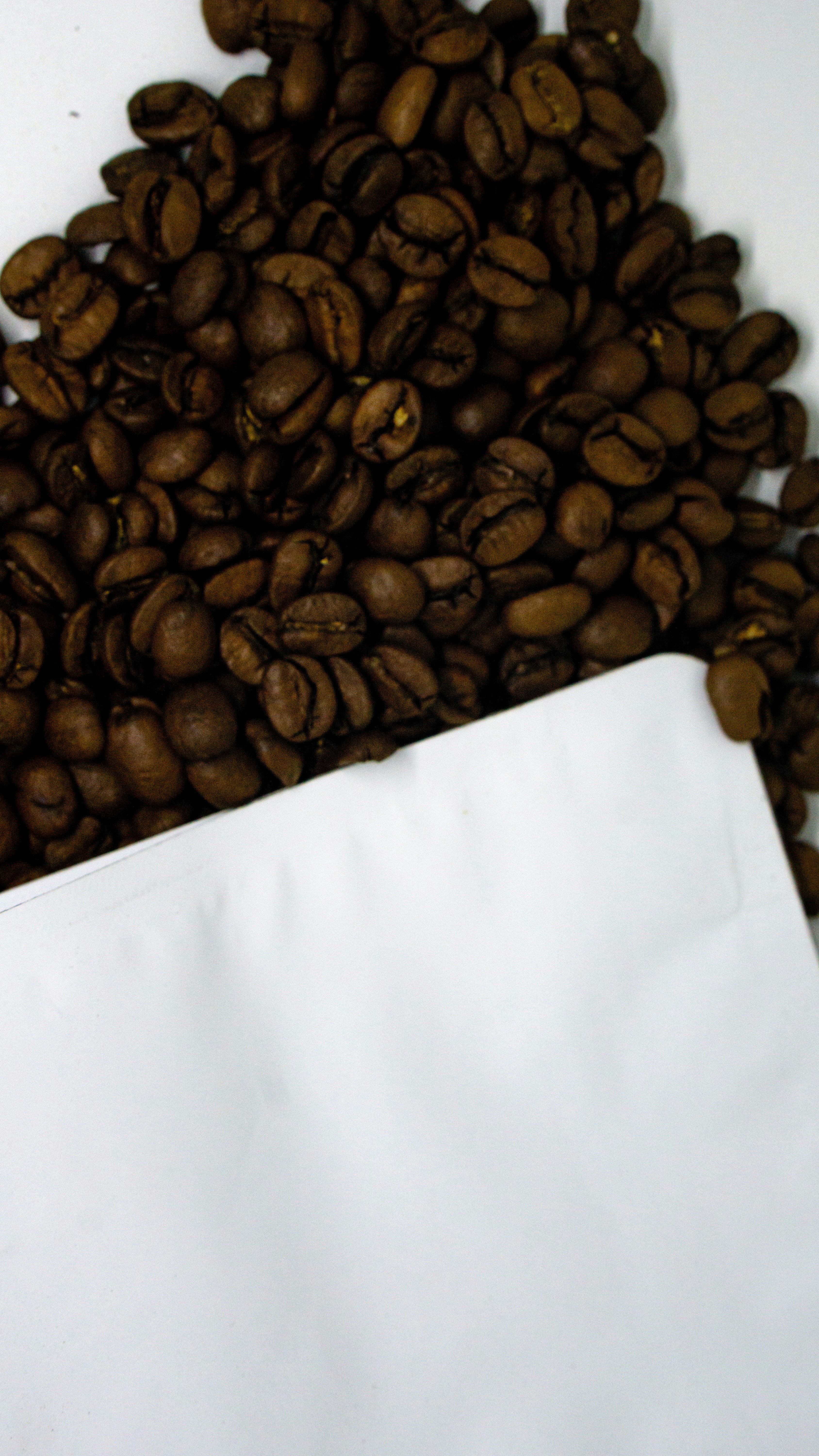a pile of coffee beans sitting next to a white paper bag
