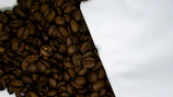 Close-up of freshly roasted coffee beans spilling from a burlap sack.
