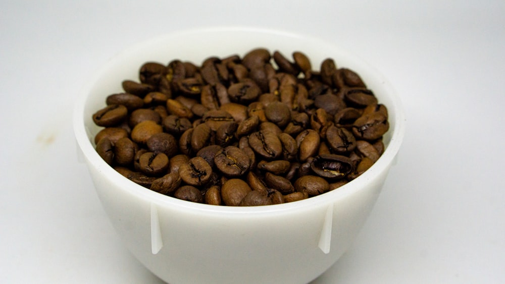 a white bowl filled with lots of coffee beans