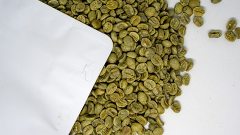 a pile of green coffee beans next to a white envelope