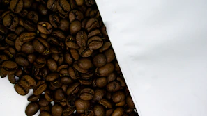Close-up of freshly roasted coffee beans spilling from a burlap sack in warm natural light