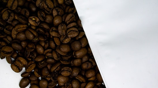A close-up of roasted coffee beans spilling from a burlap sack onto a wooden table.