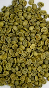 Close-up of fresh green coffee beans on a rustic wooden table with mountain scenery in the background