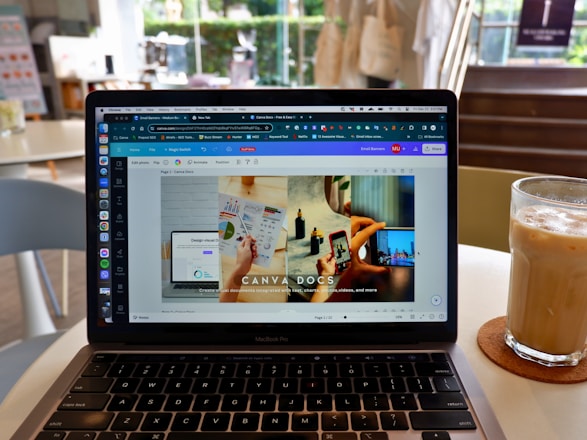 A woman happily working on her laptop creating colorful social media designs using Canva.